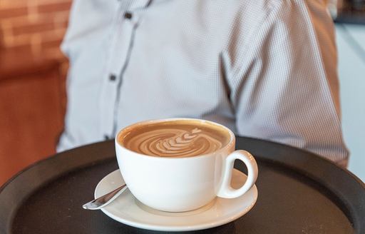 Cup of coffee held on a tray by waiter