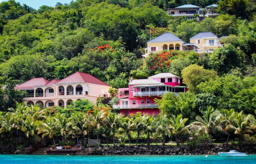 Brightly-coloured houses by the sea as seen from a luxury yacht charter in the British Virgin Islands