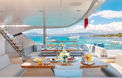 seating areas set up for breakfast on the aft deck of a superyacht 