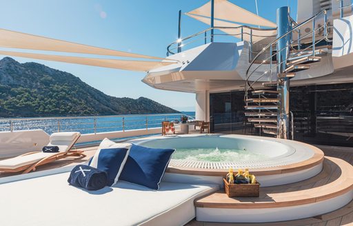 Overview of an on-deck Jacuzzi with sun pads adjacent and a staircase in the background