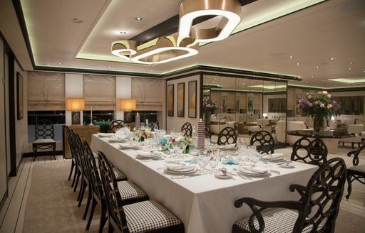 Formal interior dining table with ornate black seats onboard charter yacht PLAN B