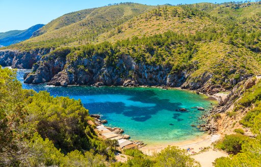 View of secluded Cala d'en Serra beach and coastal cliff rocks, Ibiza island, Spain