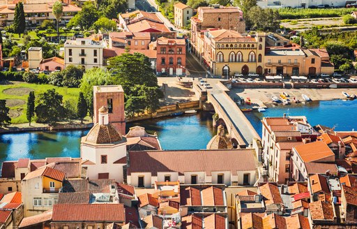 Canals in Sardinia, with beige houses lining the waterways and green trees