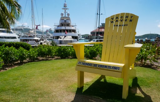 Wooden chair in foreground on grass with yachts moored in background