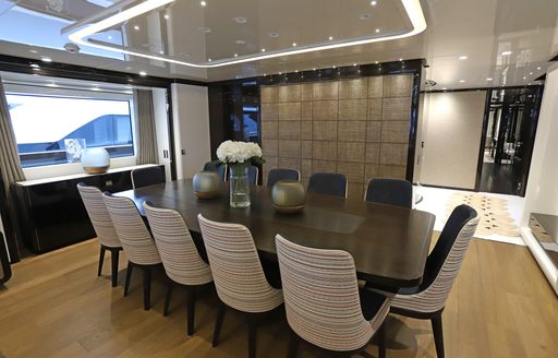 Interior dining area with long table adjacent to large window onboard charter yacht ANDIAMO