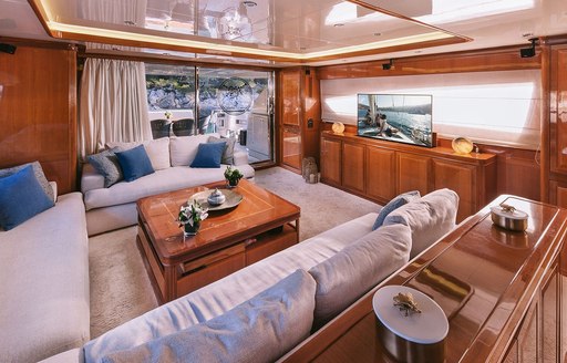 Lounge area in the main salon onboard charter yacht ELVI, plush seating facing a TV and wide window