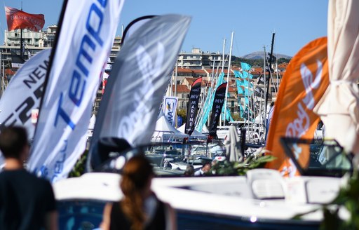 visitors on the boardwalk decorated with shipyard flags at the Cannes Yachting Festival