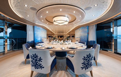 Interior dining area onboard charter yacht STARBURST IV, oval table with white and blue upholstered chairs