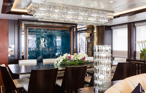 Lady Li superyacht dining set-up, with artwork on the wall and crystal chandelier on the ceiling