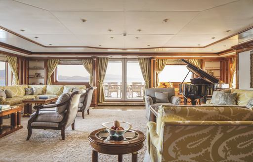 Lounge area with plush seating and a piano onboard superyacht charter TITANIA