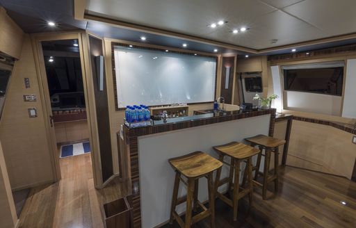 A range of wooden stools lined up at a bar in the interior of superyacht BW