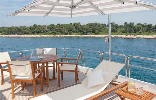 Sun deck view of table and sun loungers on board luxury yacht BRUNELLO