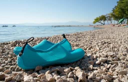Close up of blue water shoes on a pebble beach