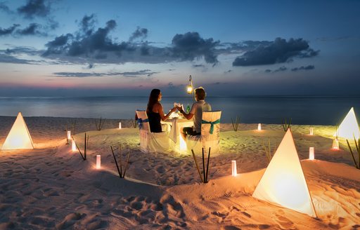 A couple of charter guests enjoying a romantic dinner on a beach in the Maldives