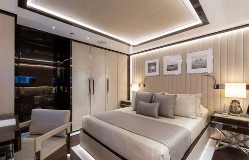 Guest cabin onboard charter yacht RESILIENCE, central berth facing forward with a gray seat in the foreground