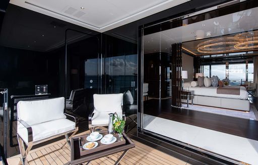 Private deck space attached to the master cabin onboard charter yacht RESILIENCE, two white seats face a small table with a berth visible in the background