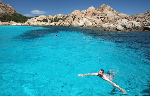 Guests of charter yacht swims in clear sea in Sardinia, Italy
