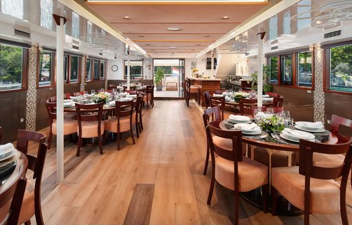 Interior dining area onboard private yacht charter QUEEN ELEGANZA, with multiple dining tables and beige seats