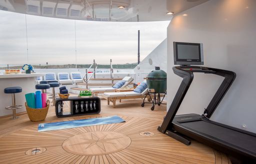 Open gym environment onboard charter yacht PURPOSE, with equipment in the foreground and exterior deck space visible in the background