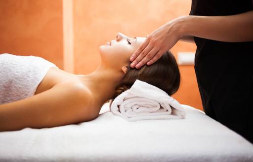 Woman lies prone receiving a head massage