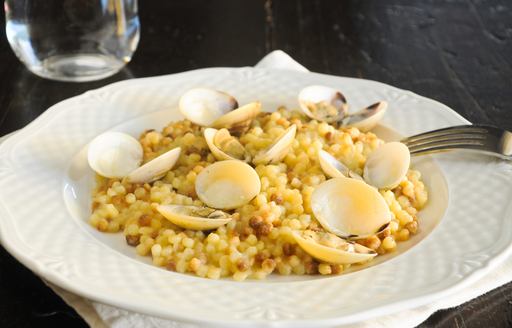 a white dish with Sardinian fregula pasta and small clams