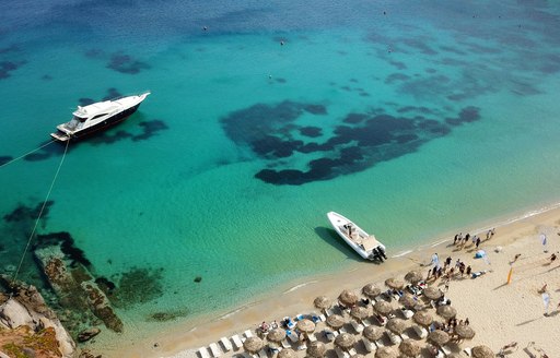 charter yachts near beach with clear blue water in greece