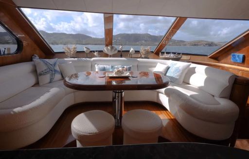 Dining area onboard charter yacht QARA, U-shaped sofa and dining table under a large window