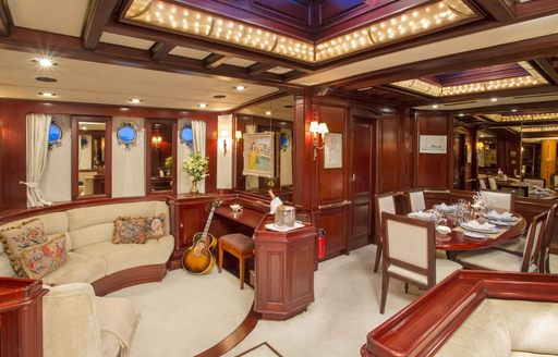 Mahogany-panelled main salon on board luxury yacht Gloria with lounge and dining areas