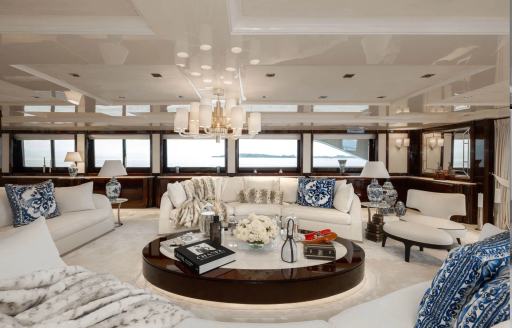 Small seating area onboard luxury charter yacht EMIR, white sofas surround a round coffee table with multiple windows behind