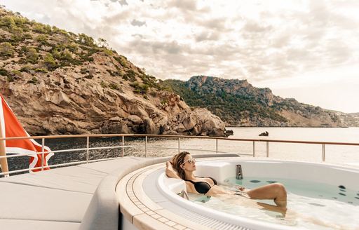 superyacht delta one jacuzzi with charter guest lying back in the water