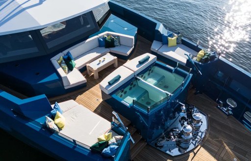 Overhead view looking down on a deck Jacuzzi and surrounding sun pads and seating onboard charter yacht KING BENJI