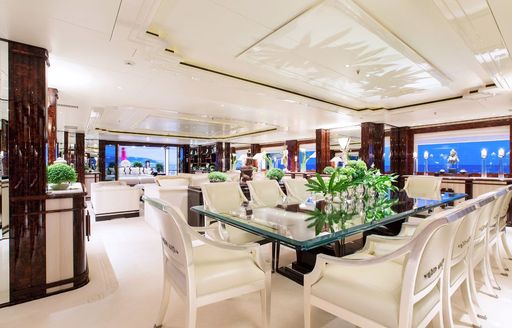 Interior dining area onboard Charter yacht 'Lioness V', formal dining table surrounded by extensive windows and white upholstery