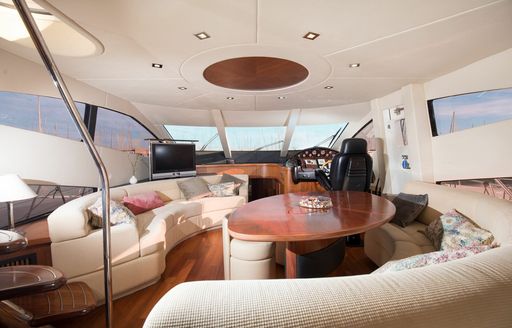 Main salon lounge area onboard private yacht charter MEDITERRANI IV, two semi-circular sofas surrounding an oval dining table