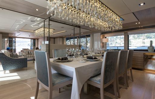 dining area looked over by a glittering light fixture in the main salon on board motor yacht THUMPER