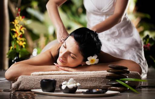 A woman indulging in a massage with flowers in Thailand