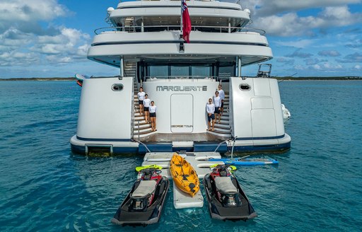 Crew line up on the aft deck with water toys on board charter yacht Marguerite