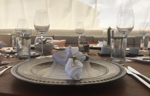 Close up of dinner plate, cutlery and glasses on board luxury yacht Zeepaard
