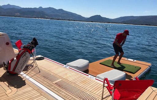 A man tees off from the aft deck of a charter yacht
