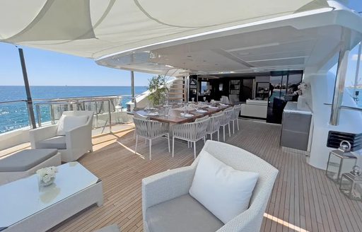 Overview of the exterior aft deck onboard charter yacht LE VERSEAU, with a lounge area and alfresco dining area.
