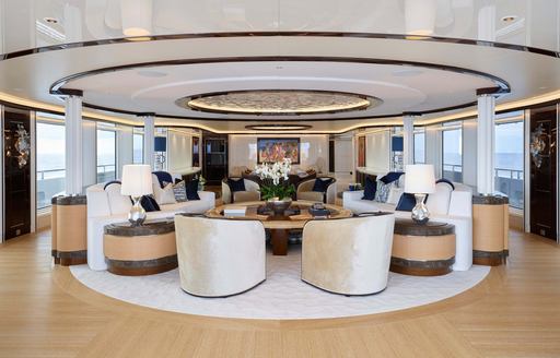 Interiors onboard super yacht charter EXCELLENCE, armchairs and sofas arranged facing in, surrounded by large windows