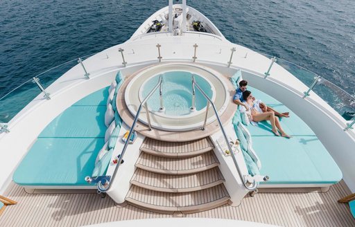 Aerial view looking down on the on-deck Jacuzzi surrounded by sun pads on the sun deck of charter yacht AIFER