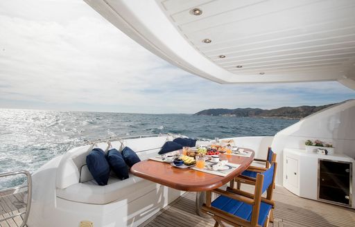 Aft main deck onboard private yacht charter MEDITERRANI IV, alfresco dining setup with views overlooking the sea