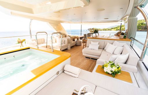 Overview of an aft deck onboard charter yacht STELLAMAR, a deck Jacuzzi is in the foreground with ample lounge seating behind