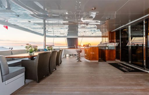 Aft main deck onboard charter yacht REMEMBER WHEN, long dining table adjacent to a wet bar and stools