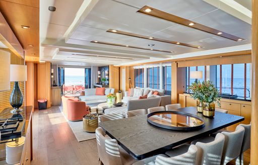 Interior dining area onboard charter yacht MAKANI II, long table surrounded by eight seats, with a lounge area in the background