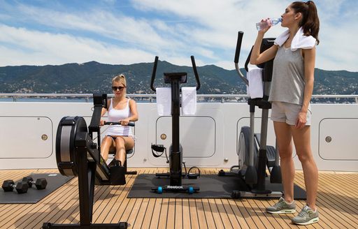 Women using a rowing machine and another drinking water
