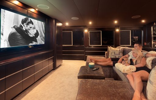 charter guests watch a movie on the widescreen TV in main salon aboard motor yacht UNBRIDLED 