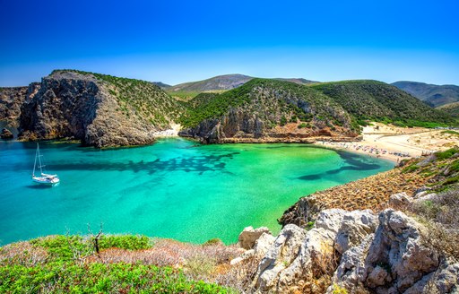 Secluded cove in Sardinia, with beautiful, bright blue water and sandy beach