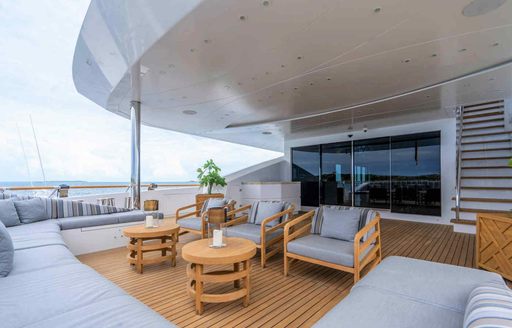 Aft main deck onboard charter yacht BABAS, lounge area with sofa, a pair of armchairs and two coffee tables