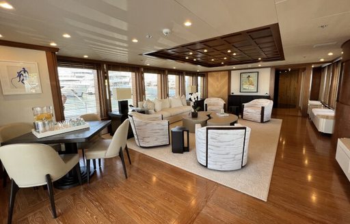 Overview of the main salon onboard charter yacht SPORT, spacious lounge aft with small table and two chairs in the foreground 